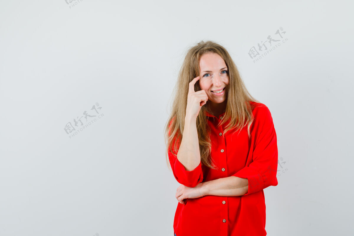 美丽金发女人穿着红衬衫站在思考的姿势 看起来很高兴 思考金发头发