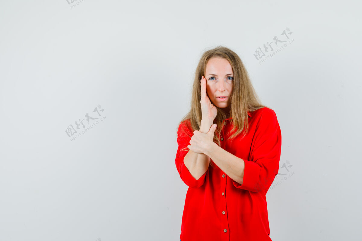 女性一个金发女人手拉着脸颊 穿着红衬衫 看上去美极了衬衫化妆品魅力