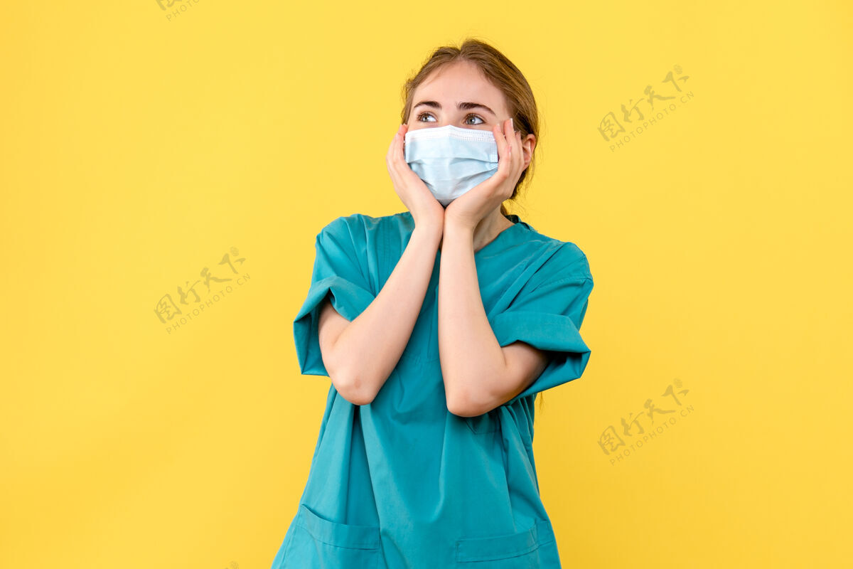 医院正面图黄色背景上兴奋的女医生医院健康病毒-大流行面具肖像女士