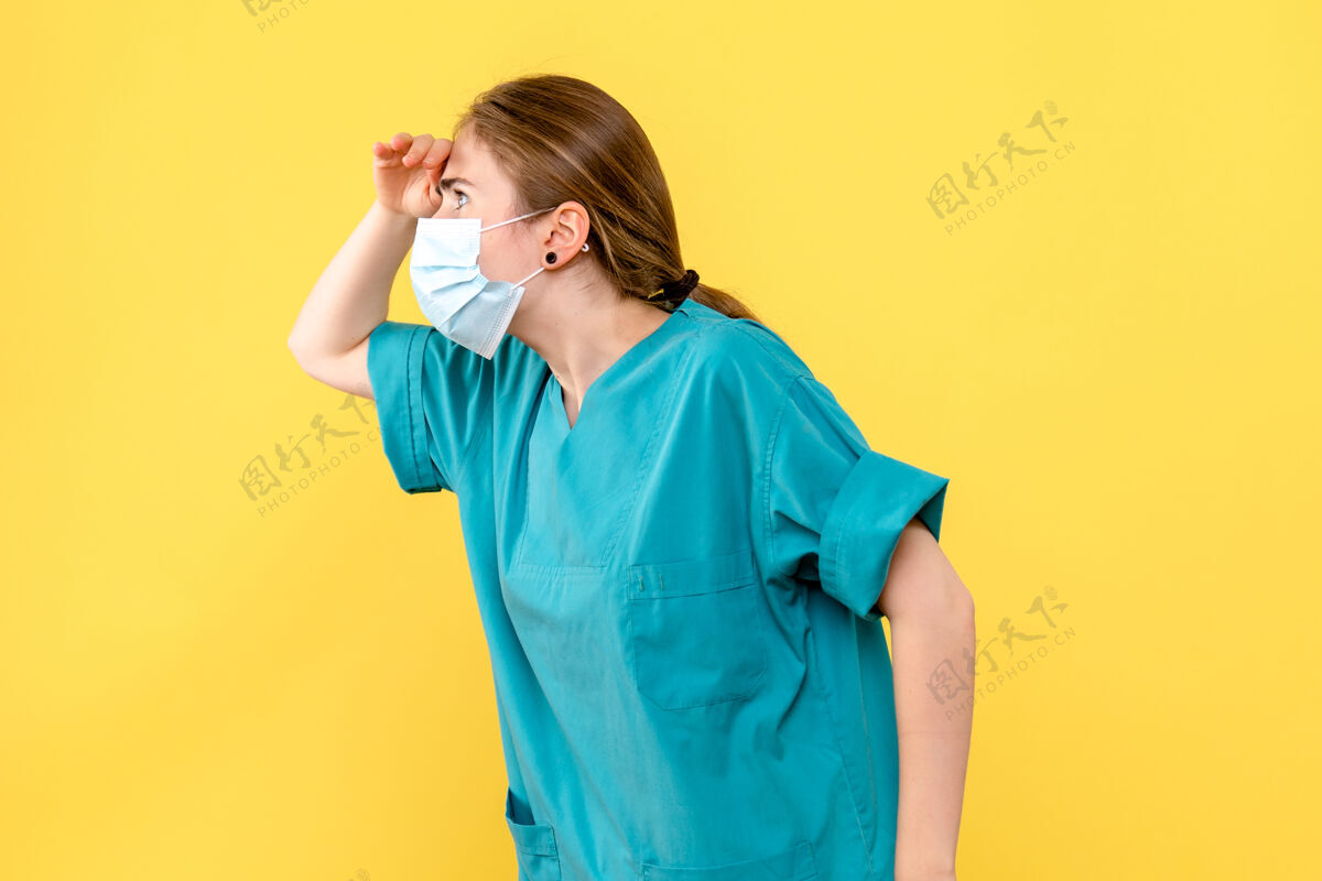 女士前视图女医生看远处黄色背景上流行的冠状病毒冠状病毒成人距离