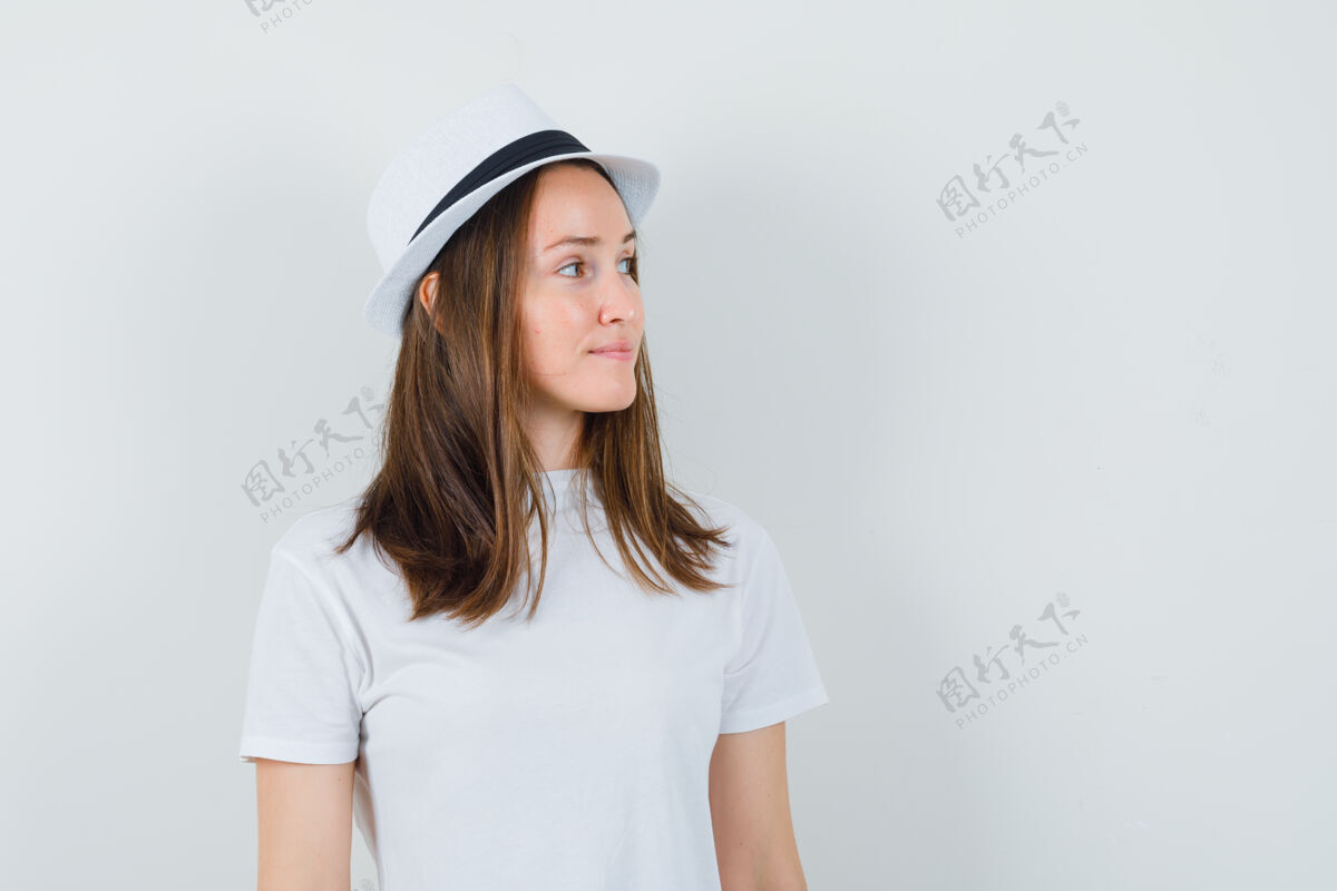 快乐年轻女孩穿着白色t恤 戴着帽子 看着旁边 看起来很优雅 前视图小随意童年