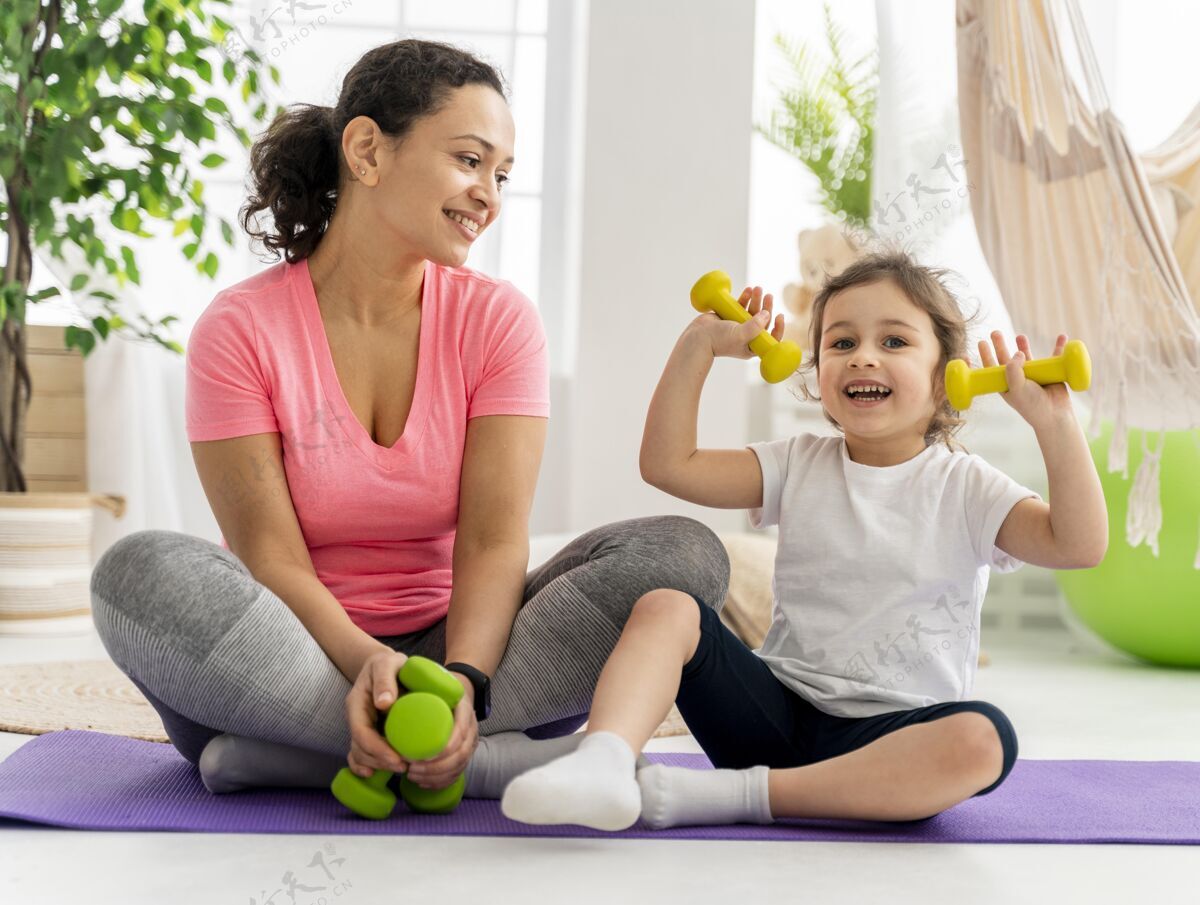 运动孩子和女人用哑铃训练健康垫子运动
