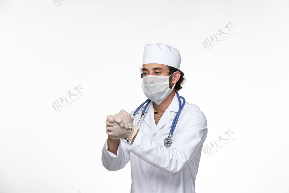 视图正面图身穿医疗服的男医生戴着口罩 以防白墙病毒疾病的传播医生防护口罩
