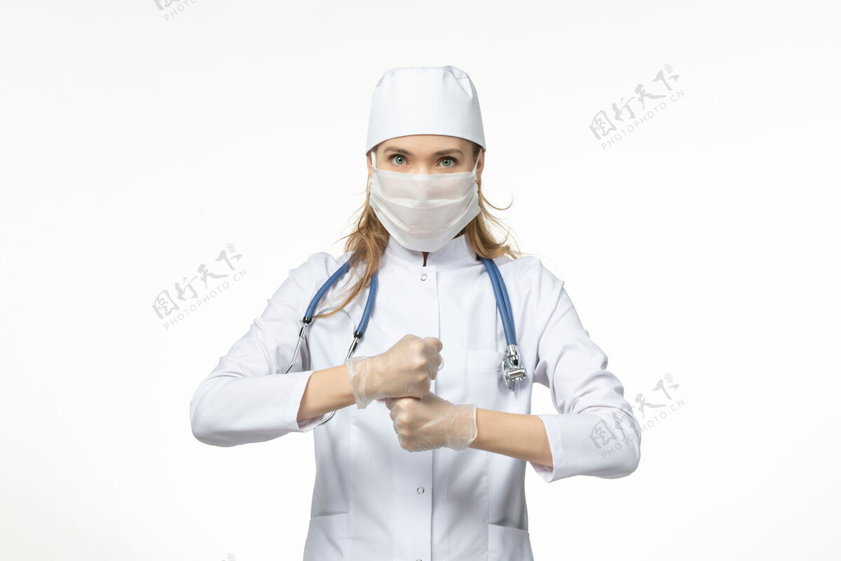医生正面图女医生穿着医疗服 戴着口罩和手套 由于白色办公桌上的冠状病毒疾病大流行健康冠状病毒手套听诊器冠状病毒
