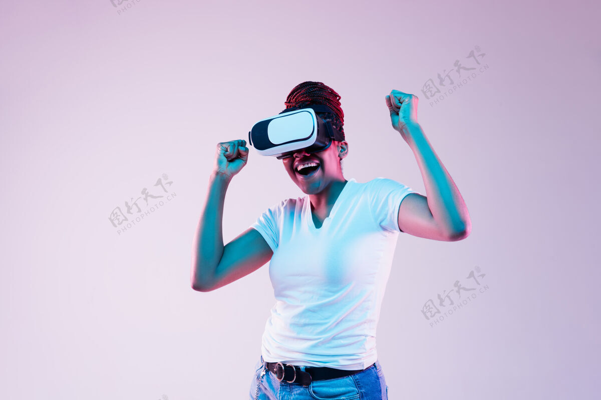 视频年轻的非洲裔美国妇女的肖像玩在虚拟现实眼镜在霓虹灯梯度背景周末美国虚拟现实