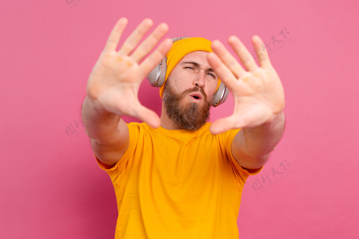 歌曲帅哥在随意地听着音乐 用耳机隔离在粉色背景上模型娱乐旋律