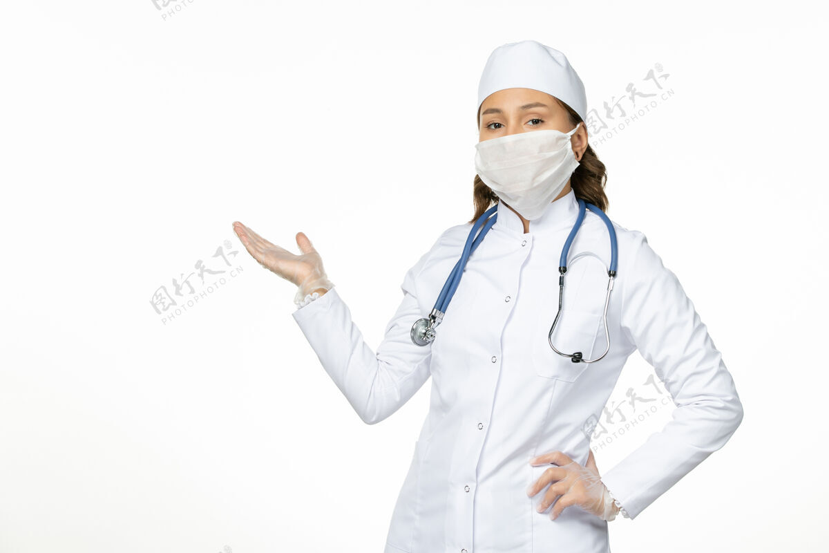 医疗正面图女医生身穿白色医疗服戴口罩因冠状病毒对淡白色墙壁大流行性疾病隔离女性视图灯光