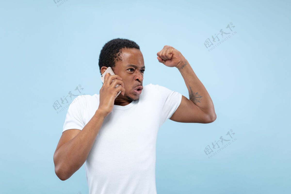 就业半身特写肖像的年轻非洲裔美国男子在白色衬衫的蓝色空间人类的情感 面部表情 广告概念广告面部人类