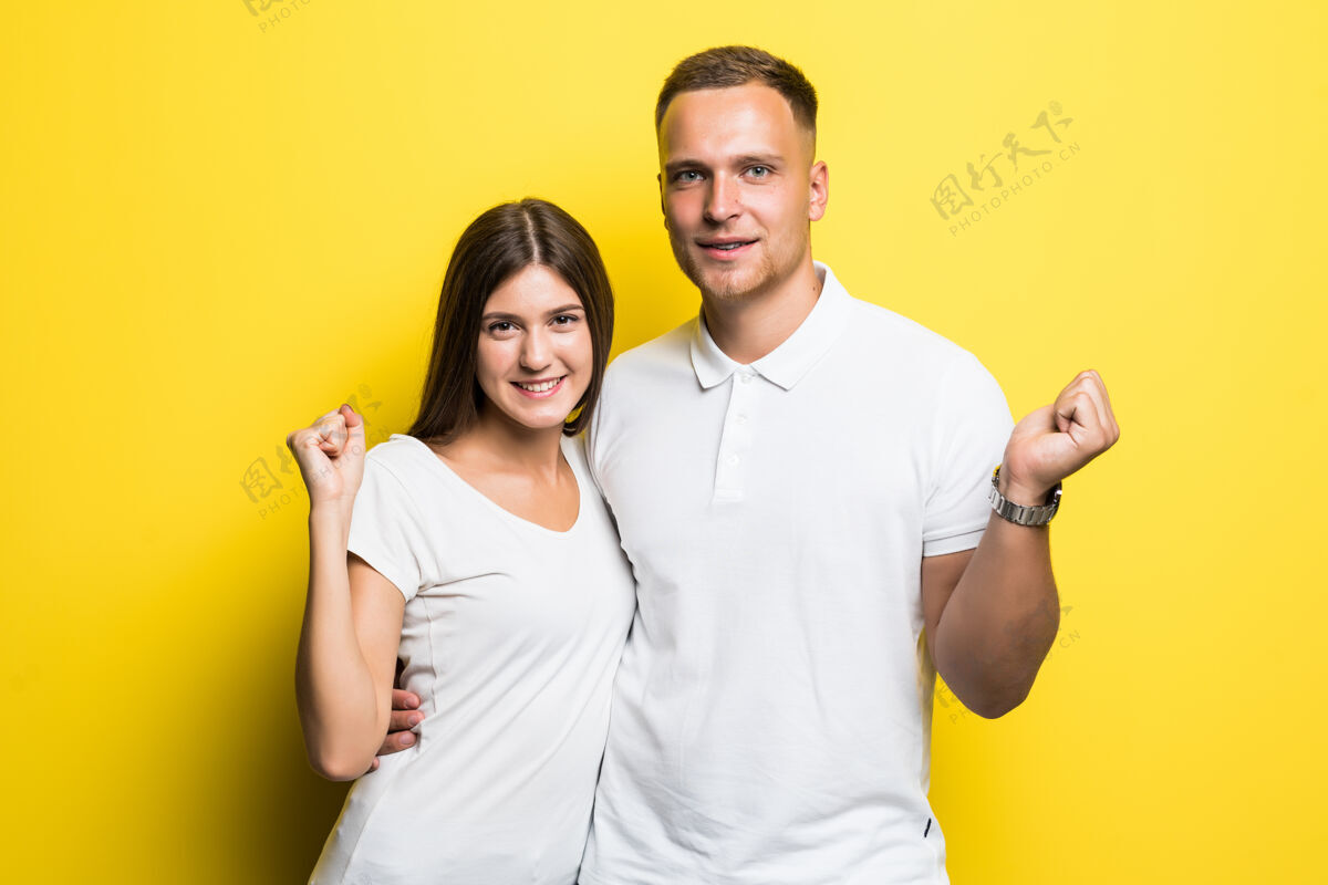 人黄色背景下的一对浪漫的情侣穿着白色t恤拥抱在一起女性男朋友笑