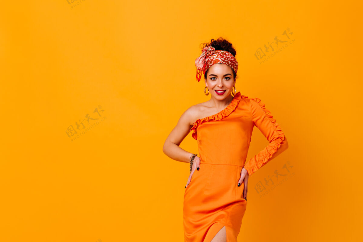 完美穿着橙色缎子裙和明亮头带的时髦女人微笑着 在与世隔绝的空间里摆姿势优雅瘦身头带