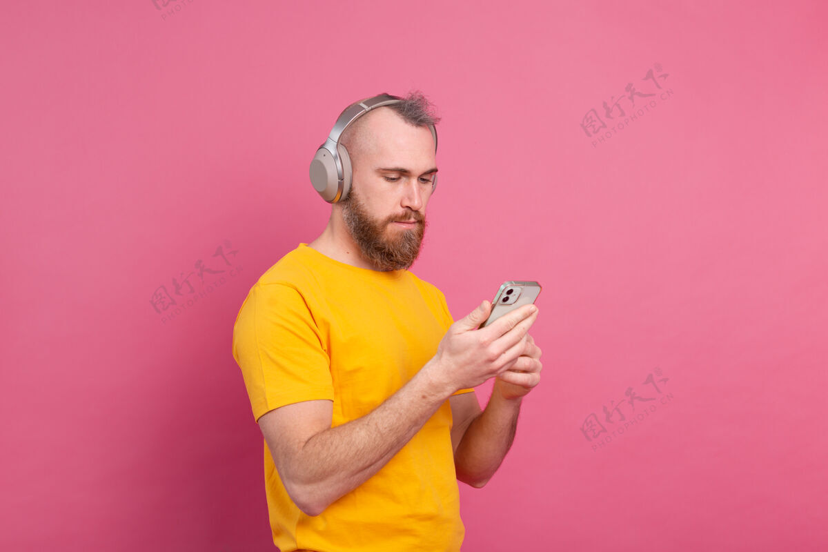 音乐帅哥在随意地听着音乐 用耳机隔离在粉色背景上无线旋律休闲