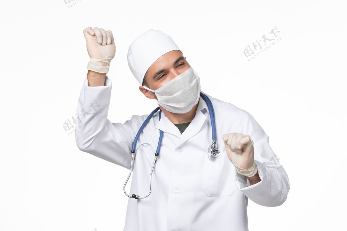 实验室外套正面图男医生穿着医疗服 戴着口罩 因在白墙上跳舞而患上了冠状病毒大流行性病毒病男性到期外套