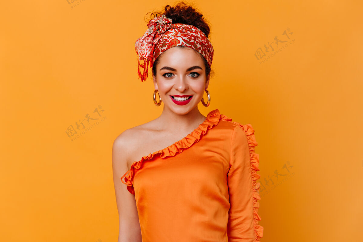 连衣裙迷人的女人戴着头巾 红唇 丝质衬衫 微笑着看着橙色空间里的相机现代时尚姿势
