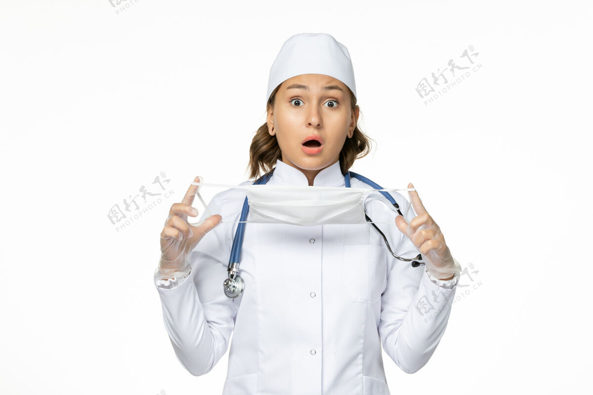 人员前视女医生身穿白色医疗服手持口罩因冠状病毒在白色办公桌上大流行性疾病病毒隔离前方病毒到期