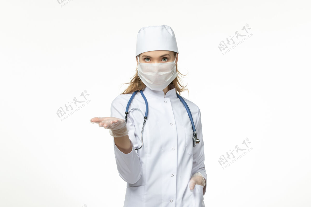 疾病正面图女医生穿着医疗服戴着口罩和手套 因白色办公桌上有冠状病毒冠状病毒-大流行性疾病病毒病套装视图面罩
