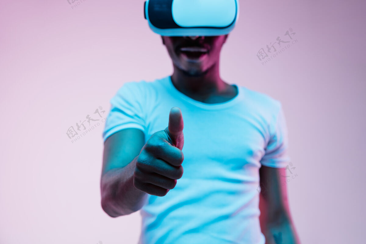 科技年轻的非洲裔美国男子在虚拟现实眼镜霓虹灯梯度背景男性肖像小玩意人类霓虹灯