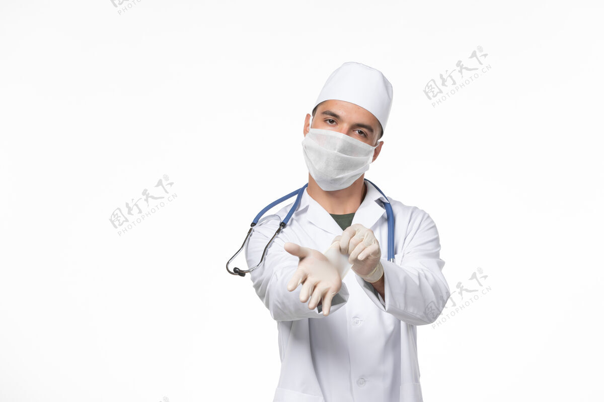视图正面图：男医生穿着医疗服 戴着防毒面具 在淡白色的墙壁上传播病毒佩戴浅白色制服