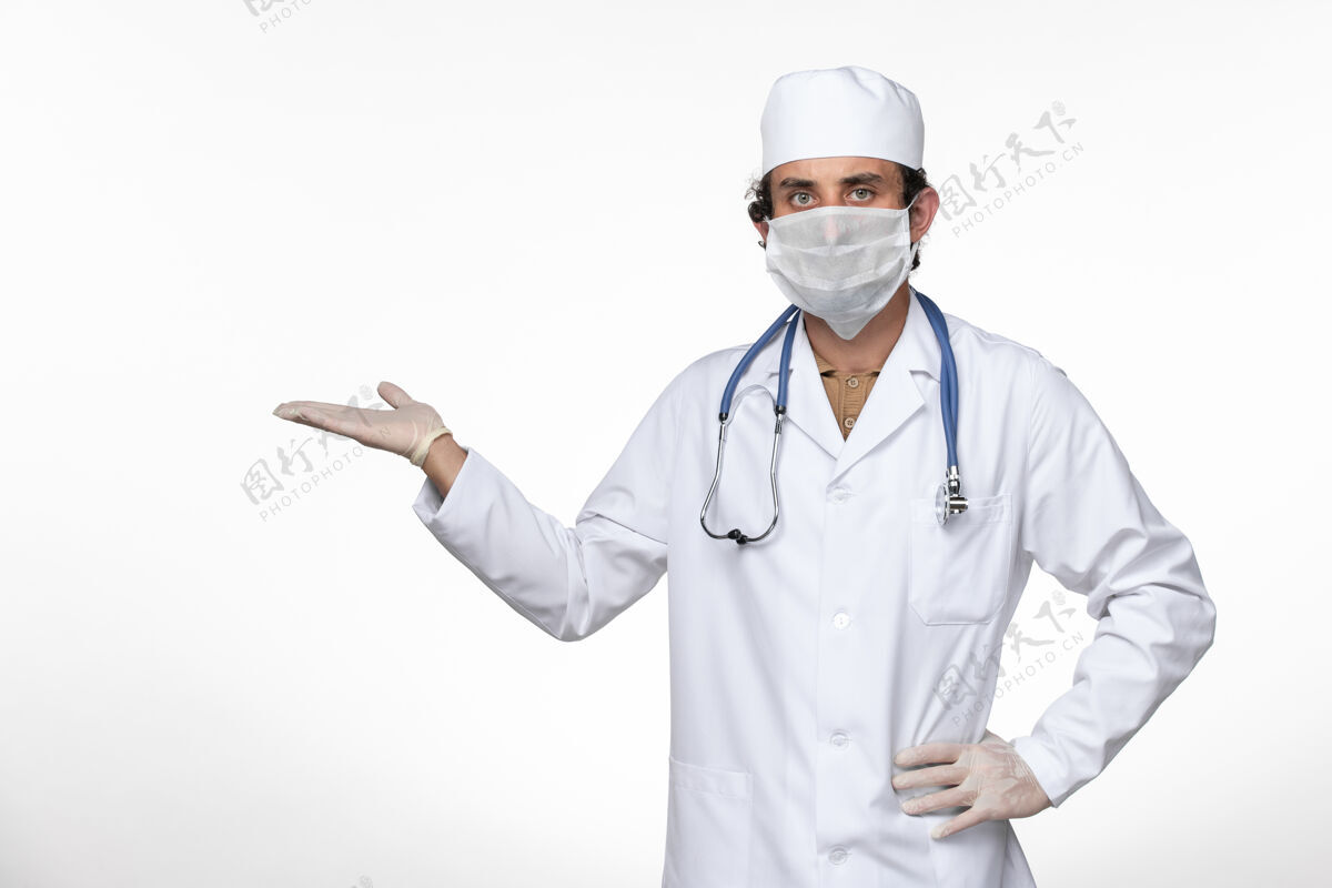 听诊器正面图身穿医疗服的男医生戴着口罩 以防白色办公桌上的冠状病毒疾病冠状病毒大流行疾病男性外套