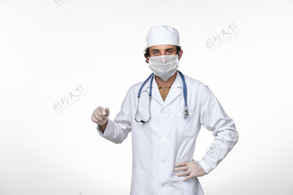 冠状病毒正面图身穿医疗服的男医生戴着口罩 以防白墙病毒疾病传播冠状病毒防护听诊器视图