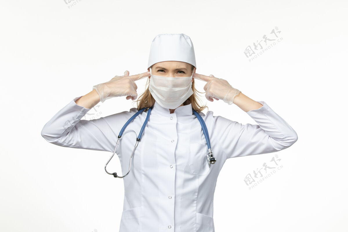 盖正面图女医生穿着医疗服戴着口罩和手套 由于冠状病毒遮住了她耳朵上的轻壁病毒冠状病毒-大流行性疾病疾病女性医生