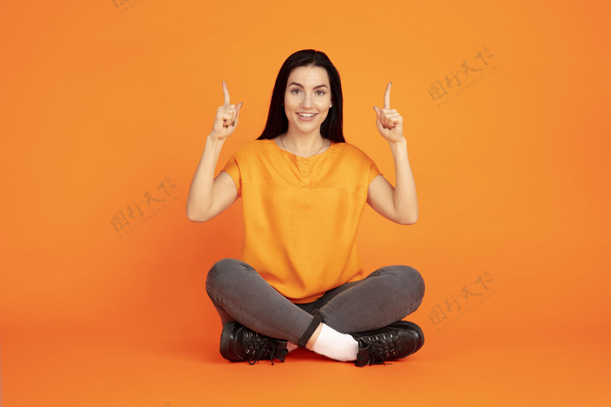 面部橙色空间上的白种人年轻女子的肖像穿着衬衫的漂亮深色女模特广告黑发女人