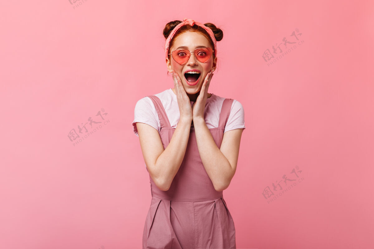 头带粉红色脸颊的女人戴着太阳镜穿粉红色裙子的红发女人的照片太阳镜眼睛肖像