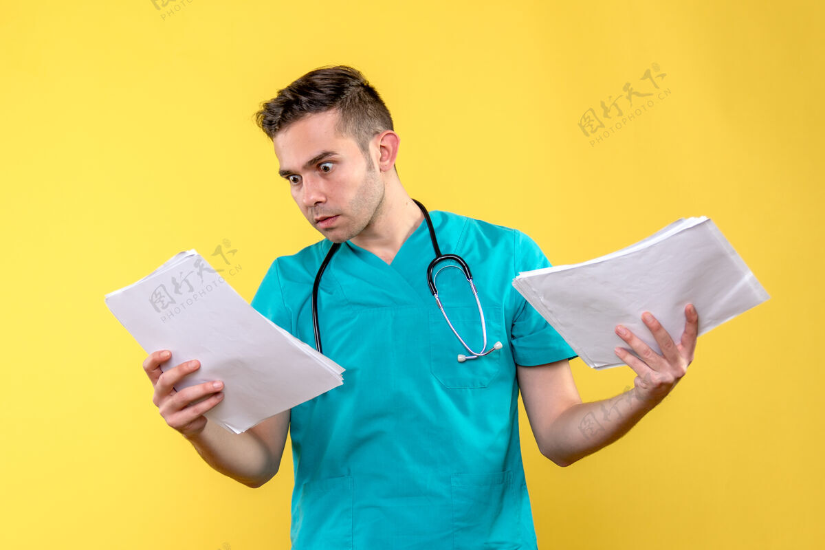 成人黄色墙上有文件的年轻男医生的正视图专业健康冠状病毒
