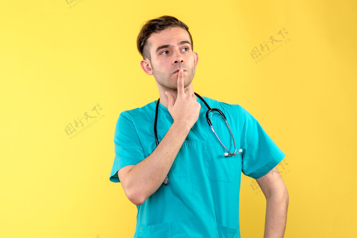 正面年轻男医生在黄墙上思考的正面图医院肖像医疗器械