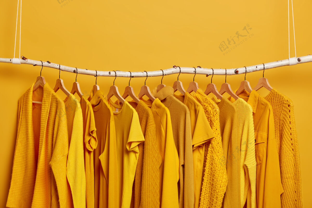 毛衣干洗后的黄色衣架不同季节的不同服装的衣柜时装店的女装选择性聚焦上面的空白处精品店衣架单色