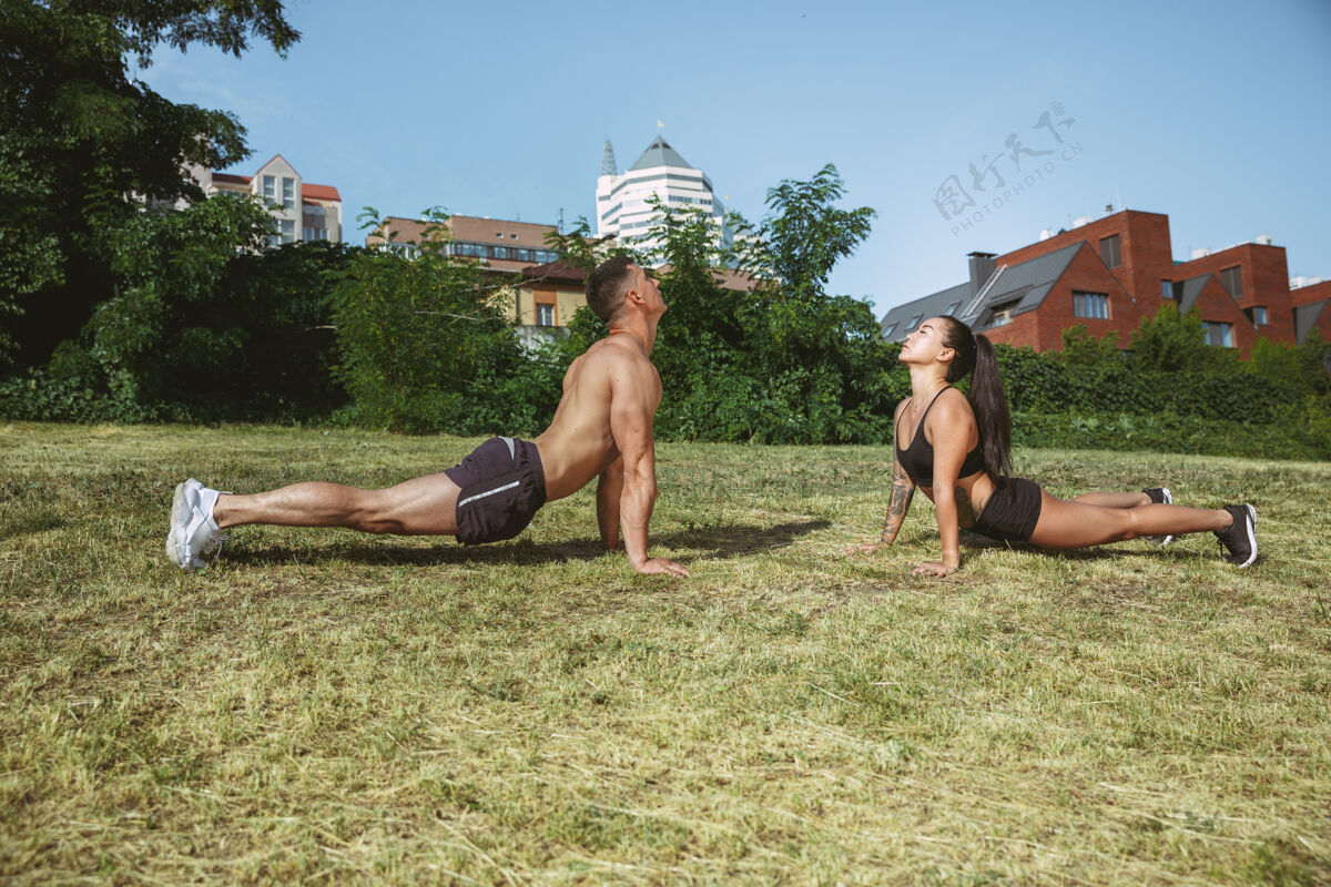 活跃一个肌肉发达的运动员在公园里做运动体操 训练 健身锻炼柔韧性夏日城市在阳光明媚的日子里在太空场上肌肉自然强壮