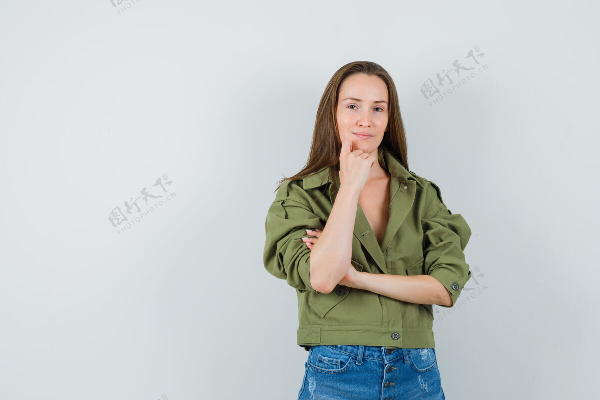 童年年轻女孩站在思考的姿势在夹克衫 短裤和看起来理智 前视图微笑肖像敏感