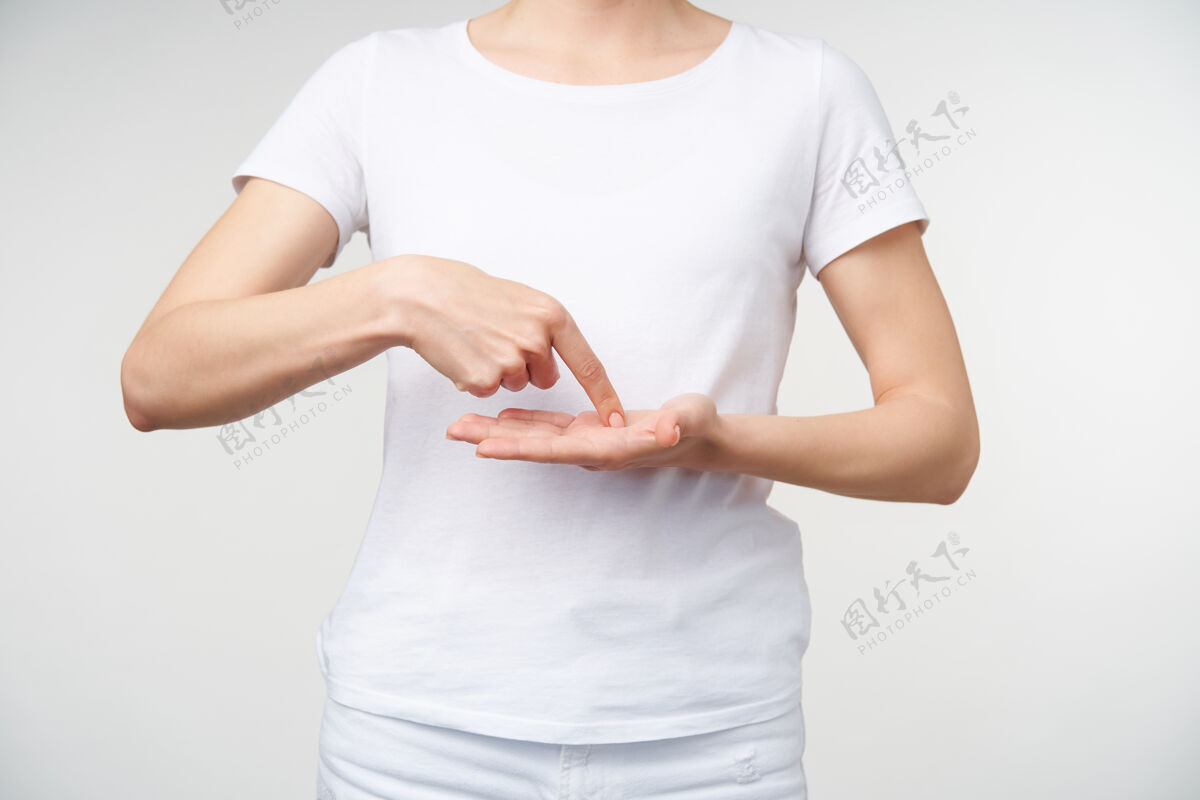 手指一张年轻女士裸体修指甲的摄影棚照片 她把食指放在凸起的手掌上 同时展示手语上的文字 站在白色背景上白色室内站立