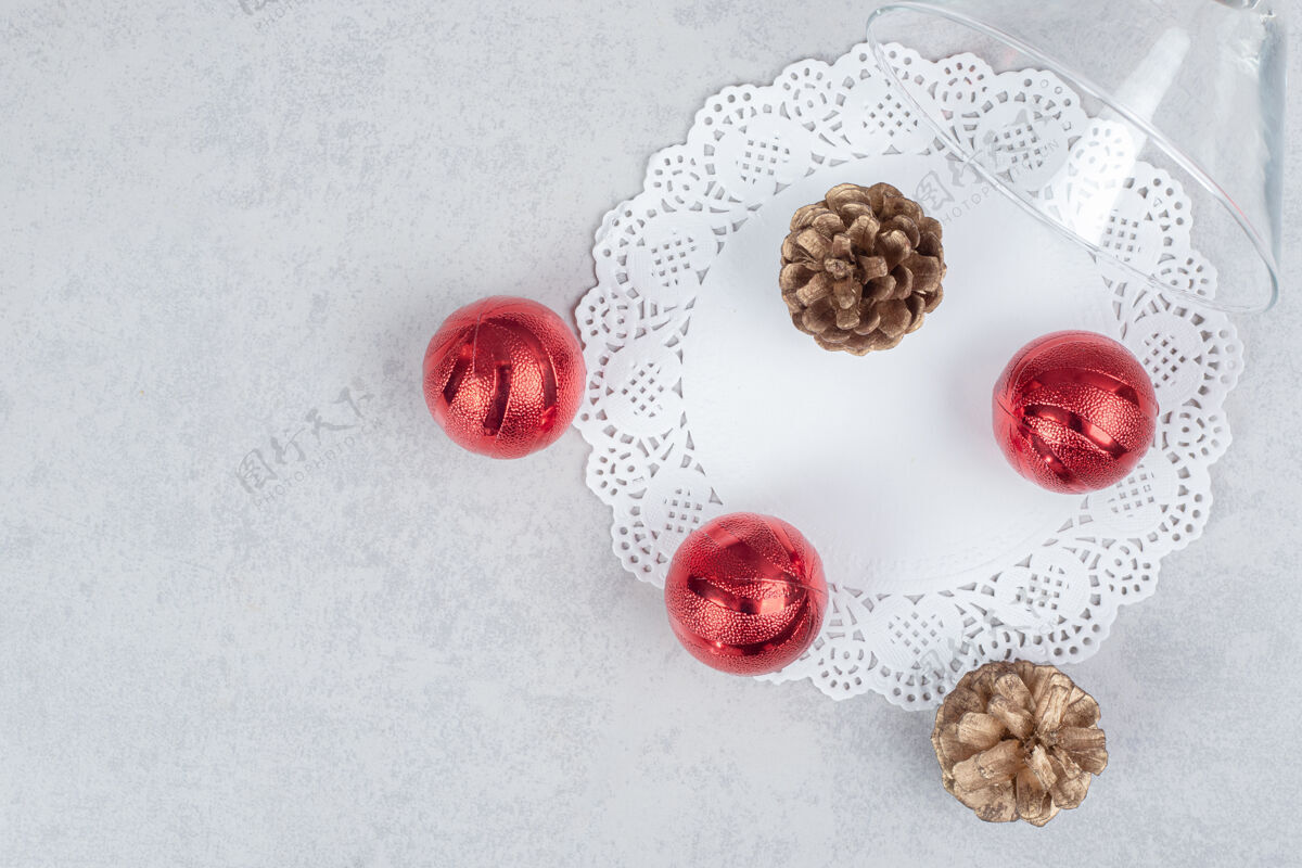 白色一杯由两个松果和三个红色圣诞球组成的白色背景高质量的照片红色玻璃球