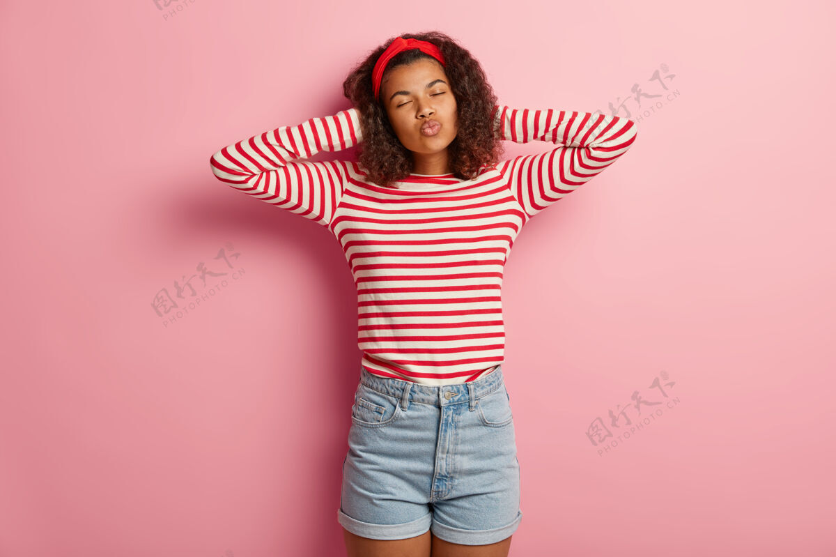 吹可爱的卷发少女穿着条纹红毛衣摆姿势的摄影棚照片短裤发型条纹