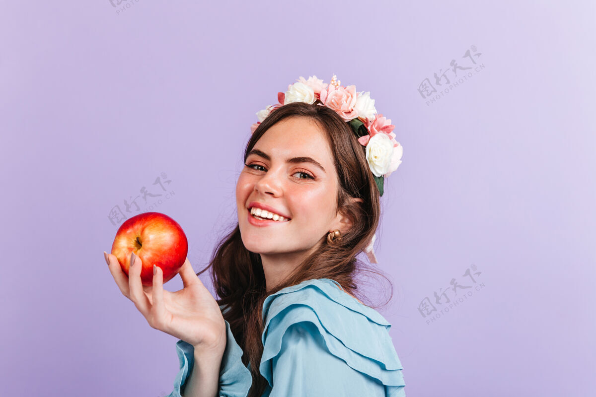 室内头发上插着玫瑰的黑发女郎手持红苹果现代白雪公主形象中女孩的特写肖像苹果黑发自信