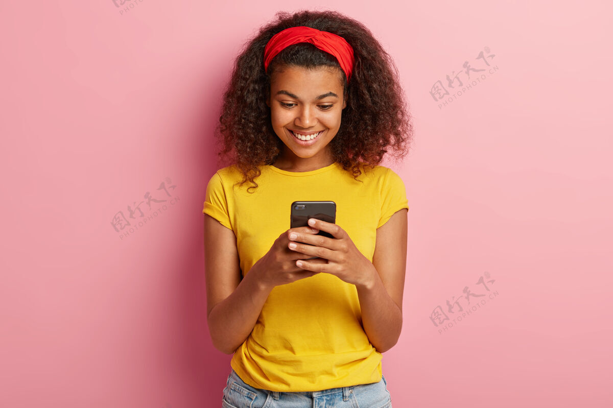 电话身着黄色T恤 留着卷发的快乐少女的画像肖像女人头带