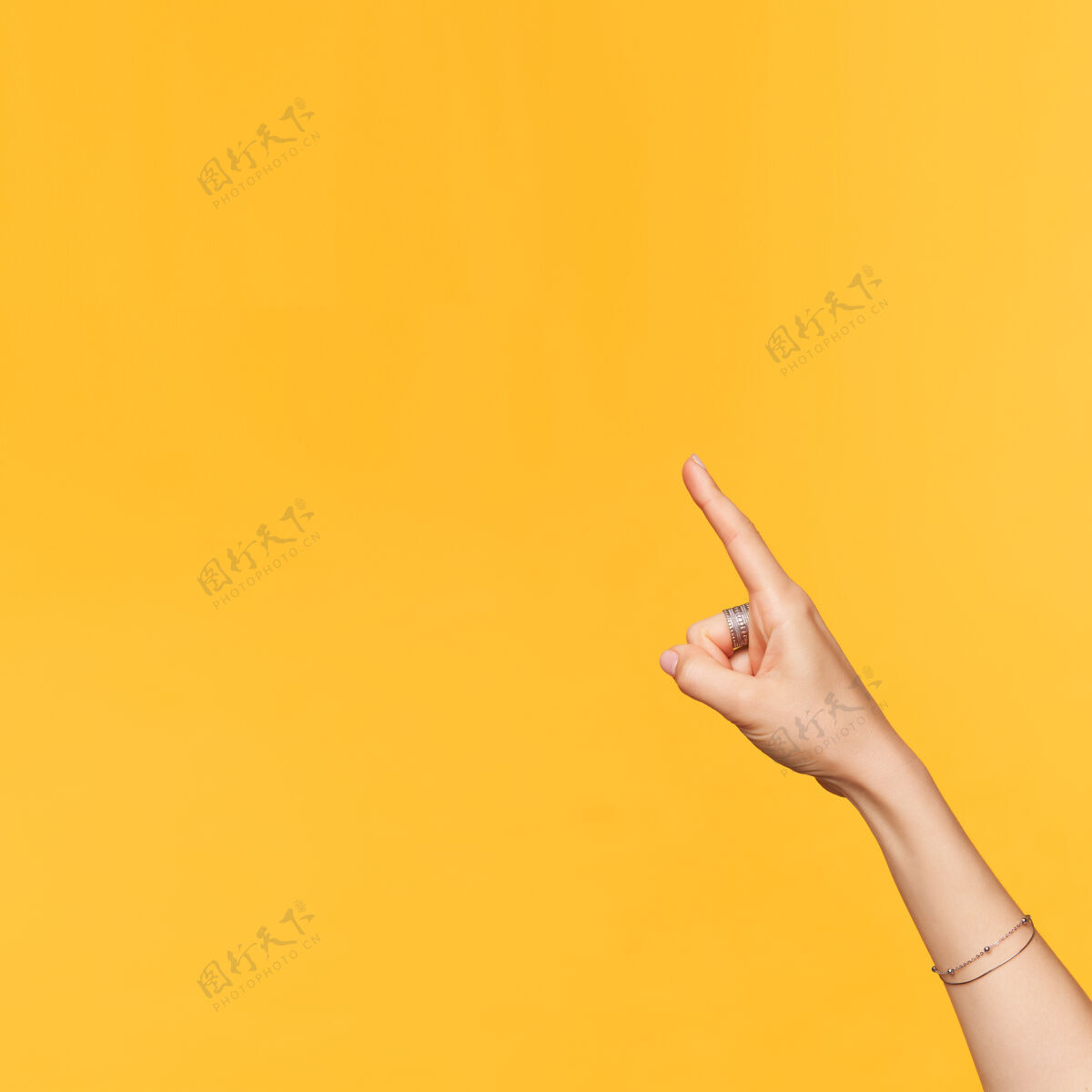 白皙侧视图年轻漂亮的手与配件被提出 而与食指向上 隔离在黄色背景肢体语言的概念食指举起特写