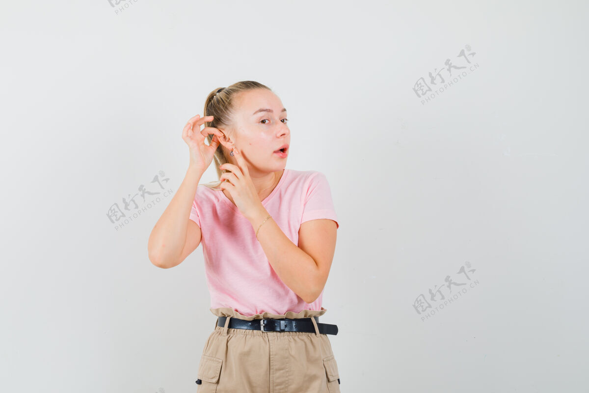 耳朵穿着t恤和裤子的年轻女士指着她的耳朵肖像女士时尚