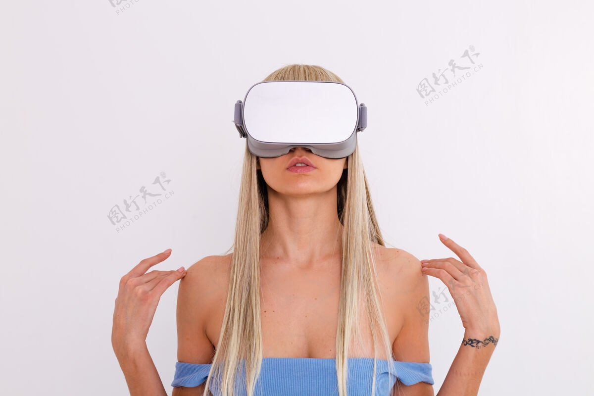 女人摄影棚照片中一个年轻迷人的女子穿着温暖的蓝色时尚西装 戴着虚拟现实眼镜在白色的不穿衣服未来科技