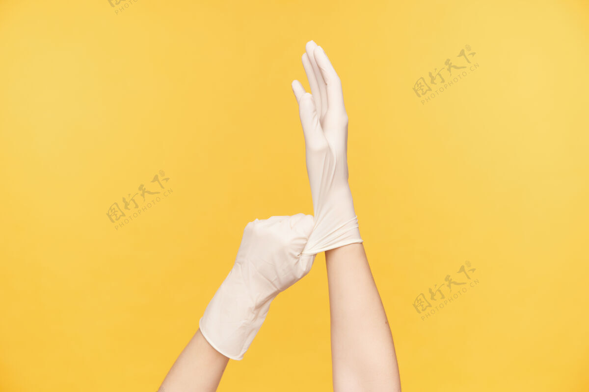成人在准备打扫房间时 抬起的女性手拿着白色橡胶手套的室内照片 在橙色背景上摆姿势人类的手概念手臂乳胶白