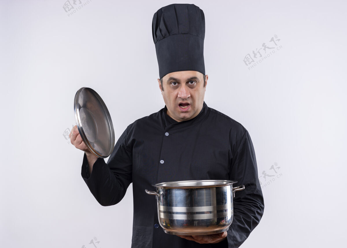 制服男厨师身穿黑色制服 头戴厨师帽 拿着平底锅 站在白色背景上看着镜头看拿着烹饪