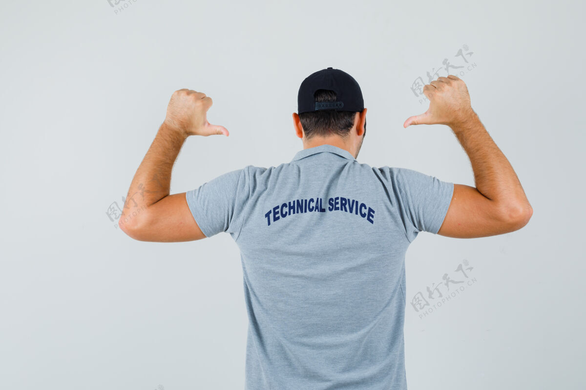 人穿着制服的年轻技术员指着他的t恤 看上去很自豪 从后面看制服专业技术