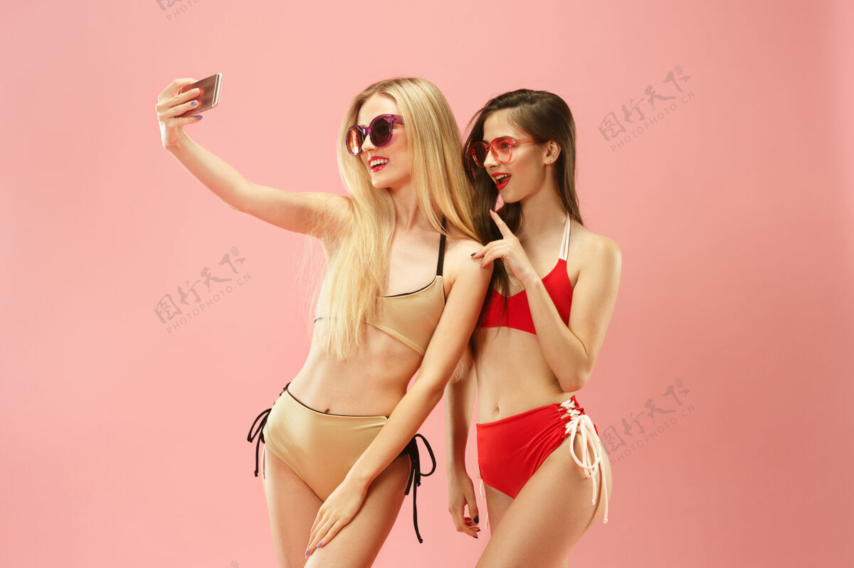 美丽穿着泳衣的可爱女孩在摄影棚摆姿势粉色背景上的夏日肖像白人青少年少年肖像微笑