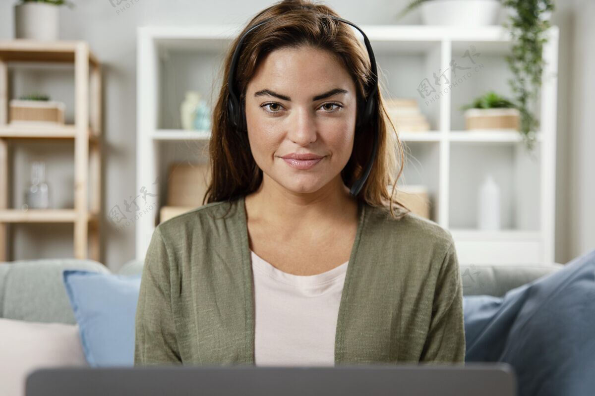 耳机带耳机的女士在笔记本电脑上进行视频通话笔记本电脑房子室内