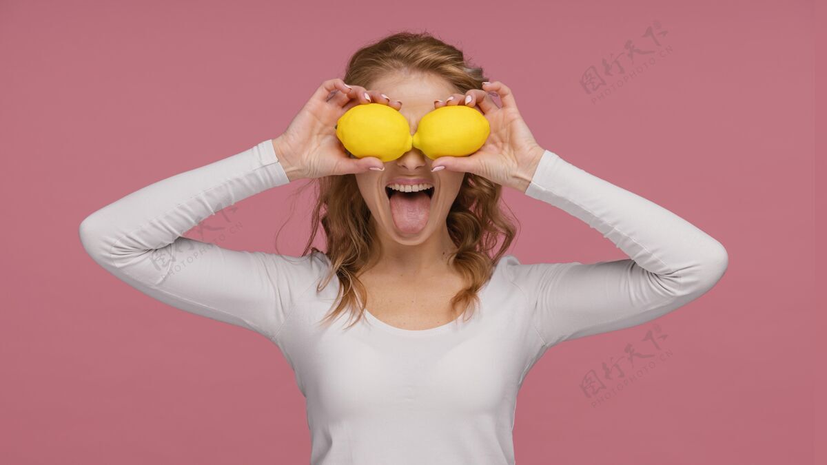 女人一个拿着柠檬和柠檬的顽皮女人的画像？笑女人模特柠檬