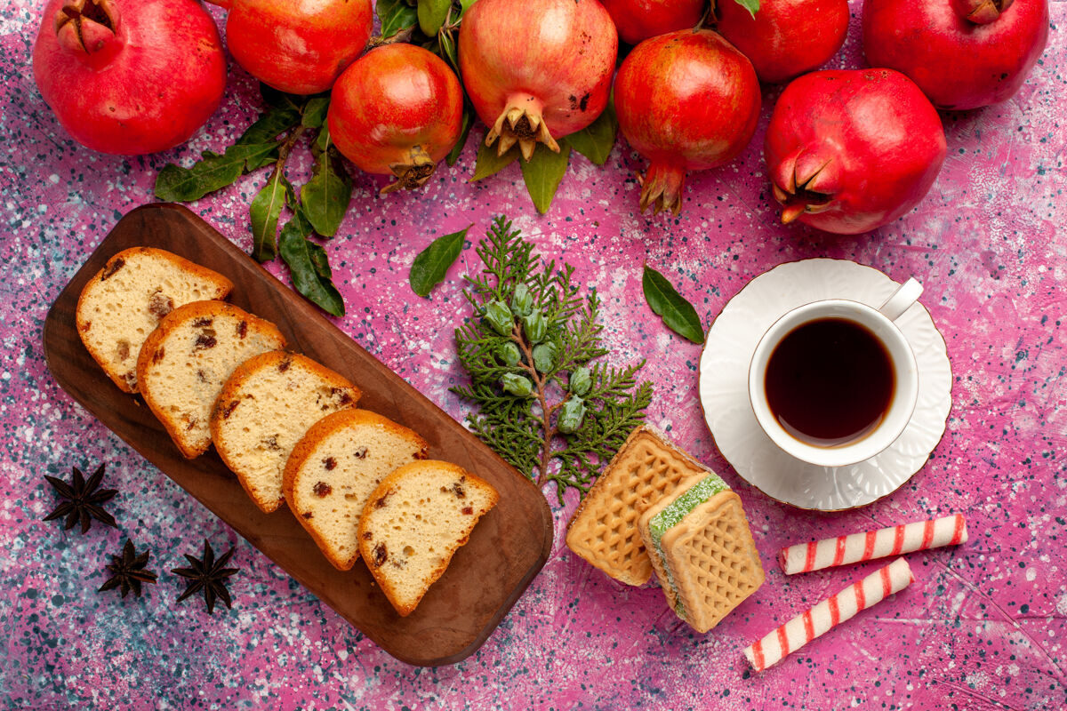 新鲜顶视图新鲜的红石榴与切片蛋糕茶和华夫饼在粉红色的表面健康茶水果