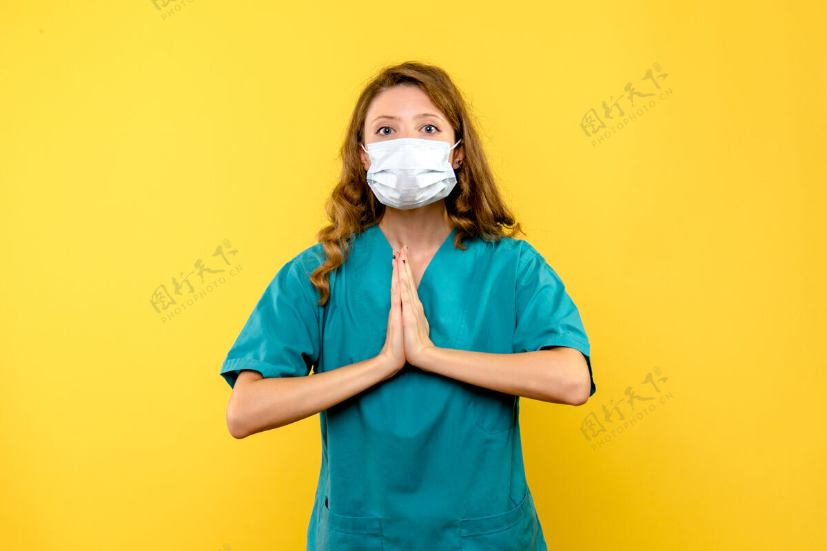 肖像正面图年轻女医生戴着面具在黄色空间祈祷头发面具人