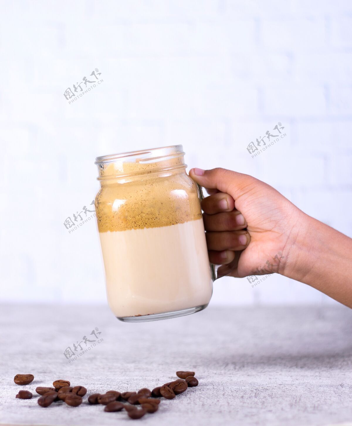 桌子一个人拿着一罐焦糖冰沙盖在咖啡豆后面的白色豆类条纹奶油