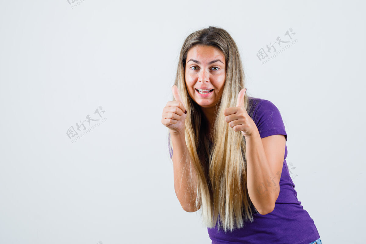 长金发女士在紫罗兰色t恤上竖起大拇指 看起来很高兴 正面视图魅力优雅时尚