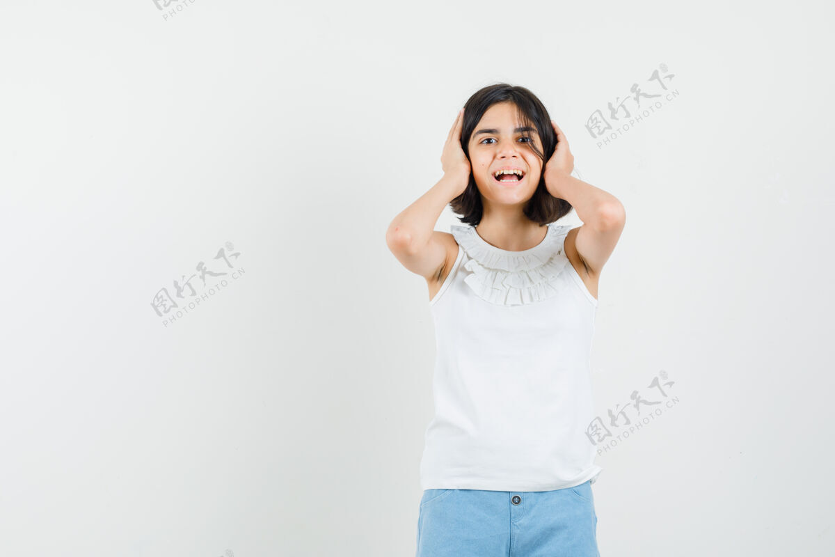 漂亮小女孩穿着白色上衣 短裤 手放在耳朵上 正面视图成人女孩手